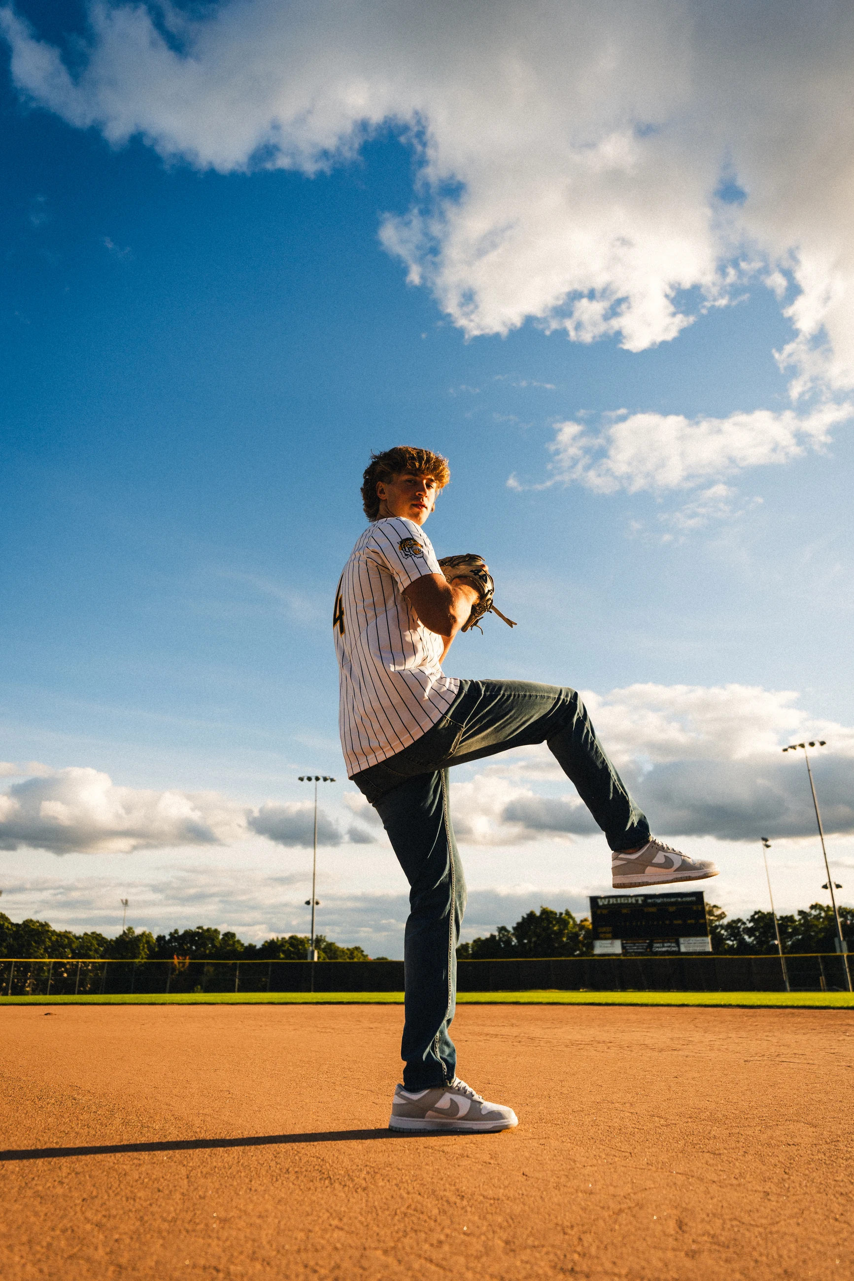 Senior baseball portrait beneath a dramatic blue sky