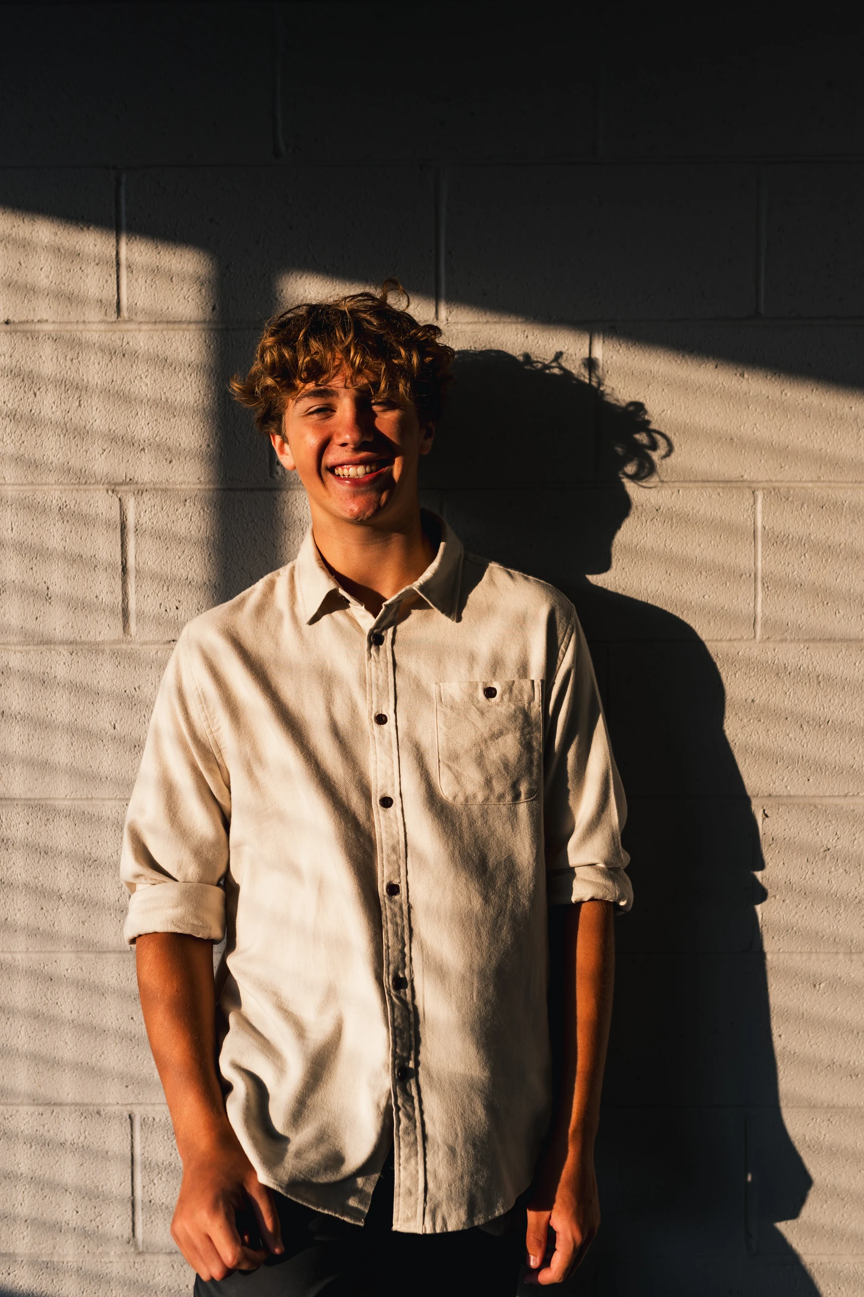 Senior portrait with a dramatic window-shadow silhouette